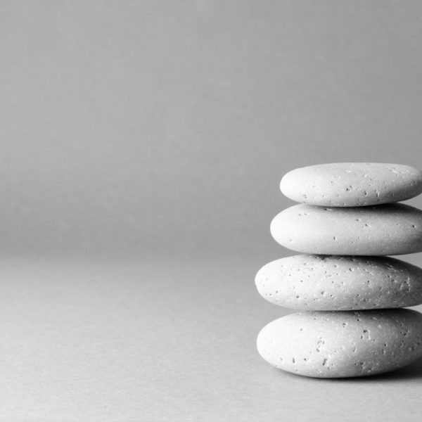 Stack of grey massage stones on gray background.